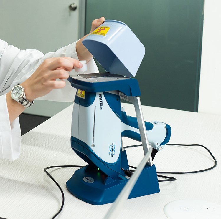 Person putting sample cup onto a portable XRF analyser.