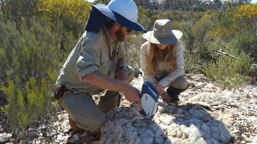 Two people with portable XRF in field analysing ground